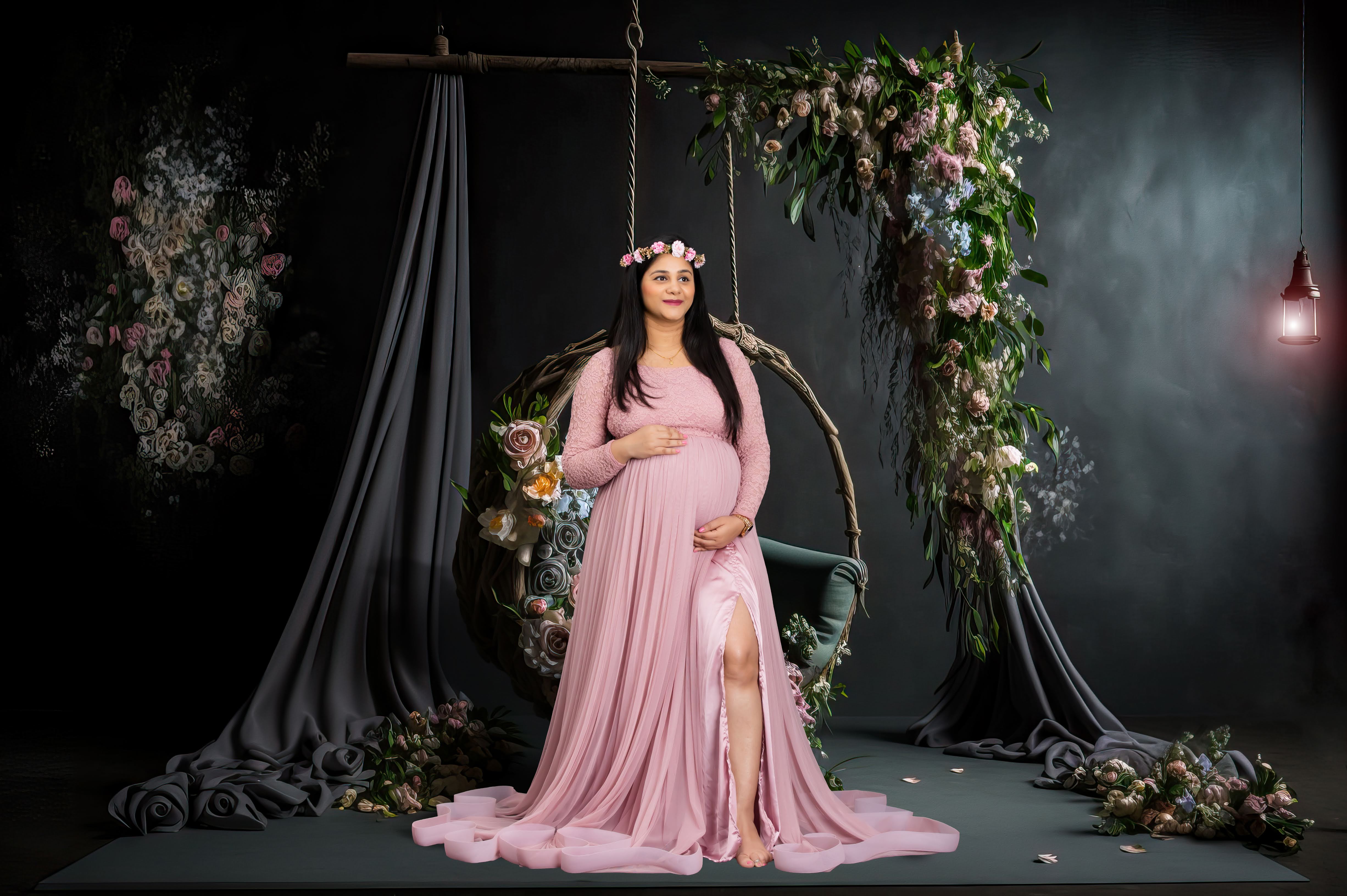 A breathtaking maternity portrait featuring a glowing mother-to-be near floral swing props.